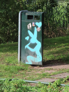 851022 Afbeelding van een afvalbak, met graffiti van een fluitspelende haas, in het Molenpark bij de Leidsche Rijn te ...